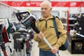 Senor man pensioner buying Upright Vacuum Cleaner in showroom of electrical appliance store