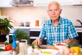 senor man preparing fresh vegetable salad at home in the kitchen Royalty Free Stock Photo