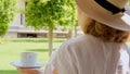 Senora female, age 50-55 in a straw hat holds a cup of hot drink and drinks coffee, sitting in the morning on a summer Royalty Free Stock Photo