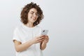 Sensing location so friend will find her in crowd. Beautiful happy caucasian woman with curly hair, standing half-turned