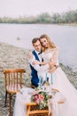 Sensitive outdoor portrait of the bride sitting on the groom on the coast. Royalty Free Stock Photo
