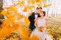 The sensitive outdoor portrait of the happy newlyweds. The groom is hugging the bride back behind the blurred yellowed Royalty Free Stock Photo