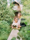 Sensitive portrait of the groom hugging the bride back in the green garden. Royalty Free Stock Photo