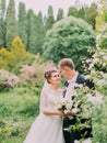 Sensitive portrait of the smiling newlyweds spending time in the blooming garden.