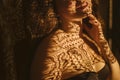 Sensitive sexy woman shoulders with a lacy shadow. Feminine and sexy. Mysterious atmospheric twilight. Warm sepia colors