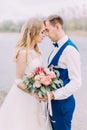 Sensitive side portrait of the newlyweds standing head-to-head with the wedding bouquet.