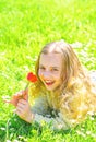 Sensitivity concept. Girl lying on grass, grassplot on background. Girl on smiling face holds red tulip flower, sniffs