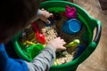 Children`s game, sensory development of the child, small toys and grain in the basin, development of an autistic child, play at