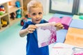 Sensory play for early brain development at nursery school. Toddler caucasian boy milk painting with his fingers, using Royalty Free Stock Photo