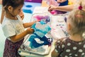 Sensory play at multi-cultural nursery school. Toddlers with their teacher playing with striped straws and milk painting Royalty Free Stock Photo