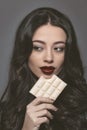 Sensual beautiful brunette young woman bite white bubbly chocolate wearing black jacket with beautiful long dark hair Royalty Free Stock Photo