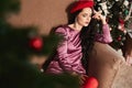 Sensual and beautiful young woman with bright makeup and closed eyes, in modish pink dress and red beret, sits near Royalty Free Stock Photo