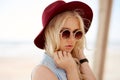 Closeup portrait of a blonde girl with round floral sunglasses,curly hair,big lips and hat, looking at the side. Royalty Free Stock Photo