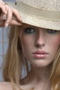 Sensual blonde woman peers out from under the brim