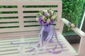 Sensual bright bouquet of fresh flowers with ribbons on the background of a white bench
