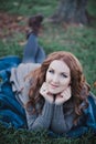 Sensual brunette lady with pout pink lips and white cheeks wearing casual cosy sweater with fur posing sit for on green grass in a Royalty Free Stock Photo