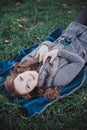 Sensual brunette lady with pout pink lips and white cheeks wearing casual cosy sweater with fur posing sit for on green grass in a Royalty Free Stock Photo