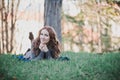 Sensual brunette lady with pout pink lips and white cheeks wearing casual cosy sweater with fur posing sit for on green grass in a Royalty Free Stock Photo