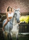 sensual brunette woman with sexy country look and horse. Portrait of a girl with brow lingerie and her horse Royalty Free Stock Photo