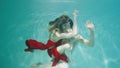 Sensual couple dancing modern choreography underwater. Woman in red and man with halfnaked torso gracefully moves in