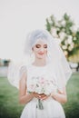 Sensual creative portrait of beautiful bride under veil holding bouquet outdoors. Gorgeous bride in white gown with modern wedding Royalty Free Stock Photo