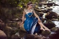 Sensual Dreaming Mermaid of Sea in Artistic Caucasian Blond Woman With Strasses on Face Sitting in Blue Wet Dress on Rocky Shore Royalty Free Stock Photo