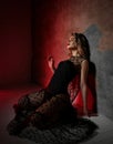 Sensual excited young blonde curly woman in transparent lace dress sits on knees on floor at wall with eyes closed