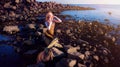 Sensual fashion model in golden top sitting on stones, nature, outdoor. Mermaid