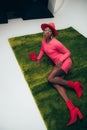 Sensual fashionable african american girl in pink dress and hat posing with bag