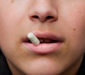 Sensual female mouth in close-up portrait with coloured pill between lips