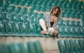 Sensual girl with long legs in the courts of a field .Long legs attractive blonde with curly hair relaxing on the chair Royalty Free Stock Photo