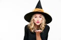 Sensual Halloween Witch Studio Portrait. Attractive young woman dressed in witch halloween costume blowing a kiss towards camera. Royalty Free Stock Photo