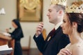 Sensual happy bride and groom wearing gold crowns during wedding ceremony in christian church, coronation ritual indoors face