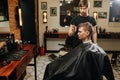 Sensual manly professional hairdresser looking client`s hair length