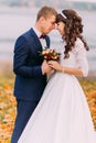 Sensual moment of young newlywed bridal couple on autumn lakeshore full orange leaves Royalty Free Stock Photo