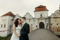 Sensual newlywed couple hugging on old bridge, beautiful brunette bride and handsome groom holding hands at sunset near stone Royalty Free Stock Photo