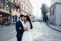 Sensual outdoor portrait. Pretty young couple of newlyweds is gently hugging in the sunny town street. Royalty Free Stock Photo