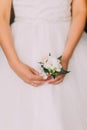 Sensual photo of young girl in white dress holding cute little boutonniere, close-up