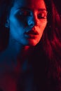 Sensual portrait of beautiful girl behind glass with raindrops with red blue lighting Royalty Free Stock Photo