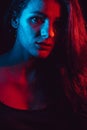 Sensual portrait of beautiful girl behind glass with raindrops with red blue lighting Royalty Free Stock Photo