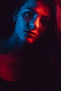 Sensual portrait of beautiful girl behind glass with raindrops with red blue lighting Royalty Free Stock Photo