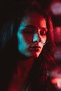 Sensual portrait of beautiful girl behind glass with raindrops with red blue lighting Royalty Free Stock Photo