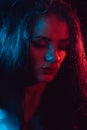 Sensual portrait of beautiful girl behind glass with raindrops with red blue lighting Royalty Free Stock Photo