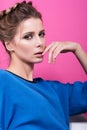 Sensual portrait of beautiful young woman in a blue sweater. Gentle touch fingers to face