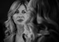 Sensual portrait of seductive middle aged woman gazing at her mirror reflection. Human emotion concept image. Black and white back Royalty Free Stock Photo