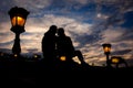 Sensual portrait of silhouette couple softly rubbing noses while sitting on the Chain Bridge near lightning street lamp Royalty Free Stock Photo