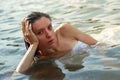 Sensual portrait of woman in white dress lying in the water. Summer emotional, beautiful portrait of a swimming woman resting in Royalty Free Stock Photo