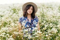 Sensual portrait of young woman in blue vintage dress and hat relaxing in summer meadow in many white wildflowers. Tranquil summer