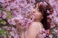 Sensual, seductive, portrait of a sexy, young, innocent, brunette woman in white dress in pink tree blossoms in april spring