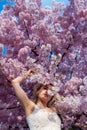 Sensual, seductive, portrait of a sexy, young woman in pink flower tree blossoms of a blossoming tree in spring